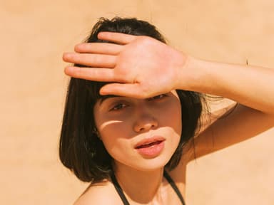 Frau schirmt Gesicht von der Sonne ab Frau schirmt Gesicht von der Sonne ab
