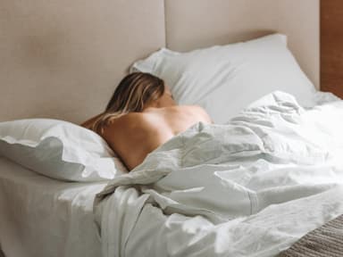 Frau liegt unbekleidet im Bett